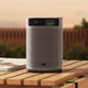 The XGIMI MoGo 2 Pro portable projector sitting on a wooden table in a backyard at dusk.